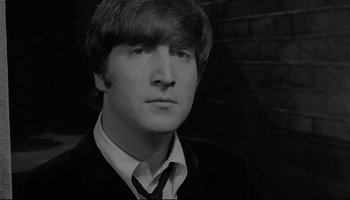 Movie still from “A Hard Day's Night” (1964), directed by Richard Lester – A man in a suit and tie in front of a brick wall; Close Up shot, High angle