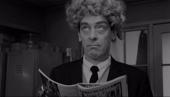 Movie still from “A Hard Day's Night” (1964), directed by Richard Lester – A man in a suit and tie holding a magazine; Close Up shot, Low angle