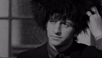 Movie still from “A Hard Day's Night” (1964), directed by Richard Lester – A black and white photo of a man with a wig on his head; Close Up shot, Low angle