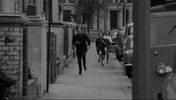 Movie still from “A Hard Day's Night” (1964), directed by Richard Lester – A man and two women running down a sidewalk; Wide shot, High angle