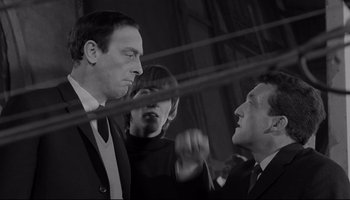 Movie still from “A Hard Day's Night” (1964), directed by Richard Lester – Two men and a woman in suits talking to each other; Medium shot, Low angle