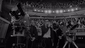 Movie still from “A Hard Day's Night” (1964), directed by Richard Lester – A group of men in suits and ties in front of an audience; Wide shot, High angle
