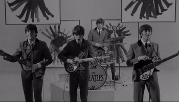 Movie still from “A Hard Day's Night” (1964), directed by Richard Lester – A black and white photo of a group of people playing instruments; Wide shot, High angle