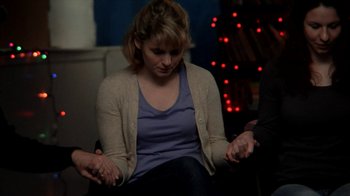 Movie still from “A Horrible Way to Die” (2010), directed by Adam Wingard – A woman sitting on a couch holding a cell phone; Medium shot, Over the shoulder angle