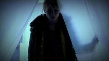 Movie still from “A Horrible Way to Die” (2010), directed by Adam Wingard – A woman in a yellow jacket standing next to a wall; Medium shot, Low angle