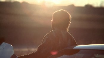Movie still from “A Horrible Way to Die” (2010), directed by Adam Wingard – A person sitting on a surfboard in the sun; Medium shot, Low angle