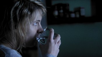 Movie still from “A Horrible Way to Die” (2010), directed by Adam Wingard – A woman drinking a glass of water in a dark room; Close Up shot, Over the shoulder angle