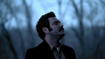 Movie still from “A Horrible Way to Die” (2010), directed by Adam Wingard – A man with a beard and a suit and tie looking up; Close Up shot, Low angle