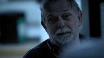 Movie still from “A Horrible Way to Die” (2010), directed by Adam Wingard – An older man with a beard is looking at the camera; Close Up shot, Over the shoulder angle