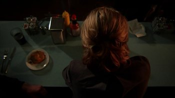 Movie still from “A Horrible Way to Die” (2010), directed by Adam Wingard – A woman sitting at a table with a plate of food in front of her; Close Up shot, Over the shoulder angle