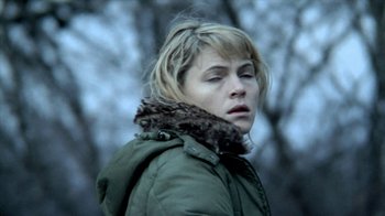 Movie still from “A Horrible Way to Die” (2010), directed by Adam Wingard – A woman in a green jacket is standing in the woods; Close Up shot, High angle