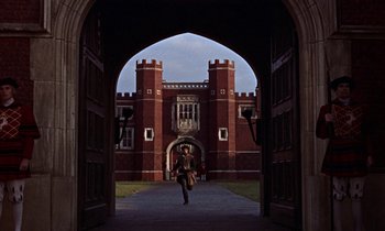 Movie still from “A Man for All Seasons” (1966), directed by Fred Zinnemann – A woman walking through an archway in front of a building; Extreme Wide shot, High angle