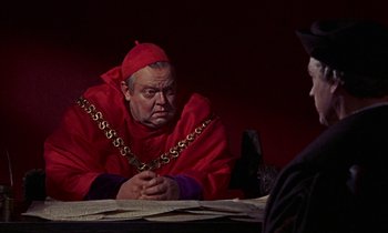 Movie still from “A Man for All Seasons” (1966), directed by Fred Zinnemann – A man in a red robe and a gold chain around his neck; Medium shot, Over the shoulder angle