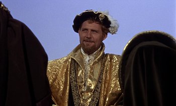 Movie still from “A Man for All Seasons” (1966), directed by Fred Zinnemann – A man in a gold suit and a black hat; Medium shot, Over the shoulder angle
