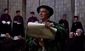 Movie still from “A Man for All Seasons” (1966), directed by Fred Zinnemann – A man in a green robe holding a sheet of paper; Medium shot, High angle