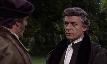 Movie still from “A Man for All Seasons” (1966), directed by Fred Zinnemann – A man wearing a black coat and a brown hat talking to another man wearing a brown hat; Close Up shot, Over the shoulder angle