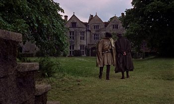 Movie still from “A Man for All Seasons” (1966), directed by Fred Zinnemann – Two men in trench coats are standing in front of an old mansion; Wide shot, High angle