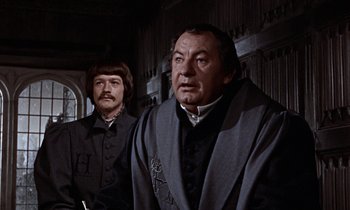 Movie still from “A Man for All Seasons” (1966), directed by Fred Zinnemann – Two men standing next to each other in front of a wall; Medium shot, Over the shoulder angle