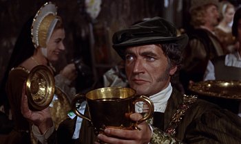 Movie still from “A Man for All Seasons” (1966), directed by Fred Zinnemann – A man holding a gold cup while wearing a hat; Close Up shot, Low angle