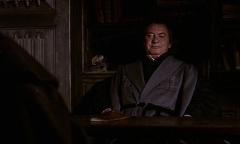 Movie still from “A Man for All Seasons” (1966), directed by Fred Zinnemann – A man sitting at a table in a dark room; Medium shot, Over the shoulder angle