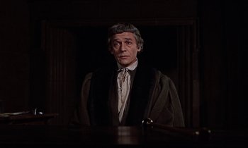 Movie still from “A Man for All Seasons” (1966), directed by Fred Zinnemann – A man standing in front of a wooden table; Medium shot, Over the shoulder angle