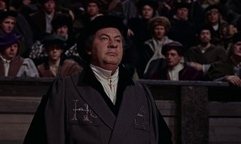 Movie still from “A Man for All Seasons” (1966), directed by Fred Zinnemann – A man wearing a black hat and a gray jacket; Medium shot, Over the shoulder angle