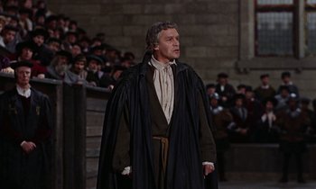Movie still from “A Man for All Seasons” (1966), directed by Fred Zinnemann – A man wearing a black cape standing in front of a group of people; Medium shot, High angle