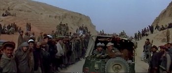 Movie still from “A Mighty Heart” (2007), directed by Michael Winterbottom – A crowd of people standing next to an army vehicle; Wide shot, High angle