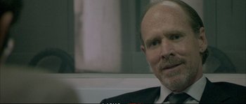 Movie still from “A Mighty Heart” (2007), directed by Michael Winterbottom – A man in a suit and tie sitting in front of a window; Close Up shot, Over the shoulder angle