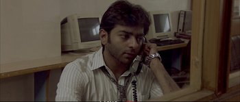 Movie still from “A Mighty Heart” (2007), directed by Michael Winterbottom – A man talking on a phone while sitting at a computer desk; Close Up shot, Low angle