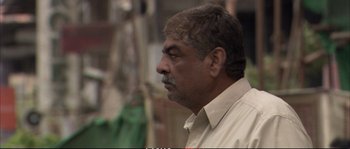 Movie still from “A Mighty Heart” (2007), directed by Michael Winterbottom – An older man with a beard and mustache looking to his left; Close Up shot, Over the shoulder angle