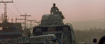 Movie still from “A Mighty Heart” (2007), directed by Michael Winterbottom – A man sitting on the top of a truck; Wide shot, Low angle