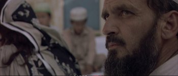 Movie still from “A Mighty Heart” (2007), directed by Michael Winterbottom – A man with a long beard is looking into the distance; Close Up shot, Over the shoulder angle