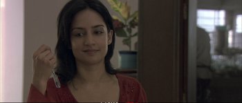 Movie still from “A Mighty Heart” (2007), directed by Michael Winterbottom – A woman in a red shirt is smiling for the camera; Close Up shot, Over the shoulder angle