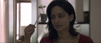 Movie still from “A Mighty Heart” (2007), directed by Michael Winterbottom – A woman is looking at the camera while holding a fork; Close Up shot, Over the shoulder angle