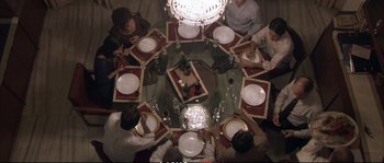 Movie still from “A Mighty Heart” (2007), directed by Michael Winterbottom – A group of people sitting around a dinner table; Wide shot, Overhead angle