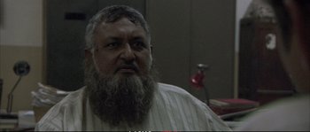 Movie still from “A Mighty Heart” (2007), directed by Michael Winterbottom – A man with a long beard is looking at the camera; Close Up shot, Low angle