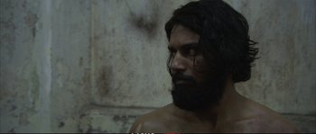 Movie still from “A Mighty Heart” (2007), directed by Michael Winterbottom – A person with long hair and a beard; Close Up shot, Over the shoulder angle