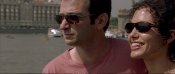 Movie still from “A Mighty Heart” (2007), directed by Michael Winterbottom – A person wearing sunglasses on the street; Close Up shot, Over the shoulder angle