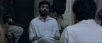 Movie still from “A Mighty Heart” (2007), directed by Michael Winterbottom – A man sitting in front of another man in front of a door; Medium shot, Over the shoulder angle