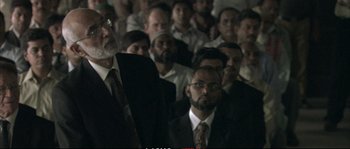 Movie still from “A Mighty Heart” (2007), directed by Michael Winterbottom – A group of men in suits and ties sitting next to each other; Medium shot, Over the shoulder angle