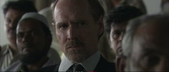 Movie still from “A Mighty Heart” (2007), directed by Michael Winterbottom – A person wearing a suit and tie; Close Up shot, Over the shoulder angle