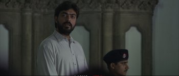 Movie still from “A Mighty Heart” (2007), directed by Michael Winterbottom – A man standing next to another man in a white shirt; Medium shot, Low angle