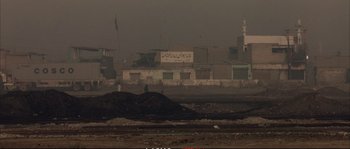 Movie still from “A Mighty Heart” (2007), directed by Michael Winterbottom – A person standing on top of a pile of dirt; Extreme Wide shot, High angle
