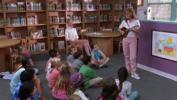 Movie still from “A Mighty Wind” (2003), directed by Christopher Guest – A group of children sitting in front of a woman playing a guitar; Wide shot, High angle