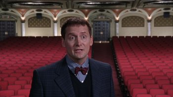 Movie still from “A Mighty Wind” (2003), directed by Christopher Guest – A man standing in front of an empty auditorium; Medium shot, High angle