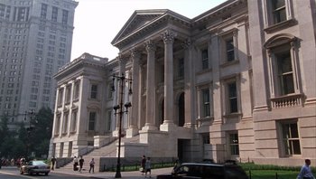 Movie still from “A Mighty Wind” (2003), directed by Christopher Guest – People walking in front of a large white building with columns; Extreme Wide shot, Low angle
