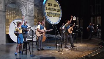 Movie still from “A Mighty Wind” (2003), directed by Christopher Guest – A group of men on a stage playing instruments; Wide shot, High angle