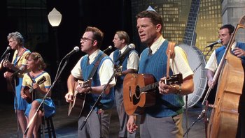 Movie still from “A Mighty Wind” (2003), directed by Christopher Guest – A group of men sing and play guitars; Medium shot, Low angle