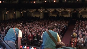 Movie still from “A Mighty Wind” (2003), directed by Christopher Guest – A crowd of people sitting in front of an audience; Wide shot, High angle